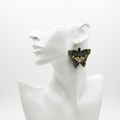SEVEN SEVENTEEN Midnight Meadow butterfly earrings featuring intricate beadwork in dark green, gold, and white tones.